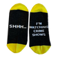 Pair of black and yellow socks with text about watching crime shows.