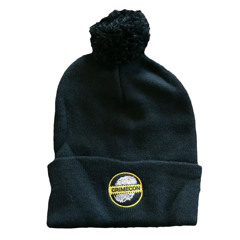 Black knit beanie with a pom-pom and circular logo patch.