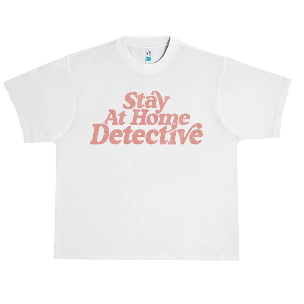 White t-shirt with pink text reading ’Stay At Home Detective’.